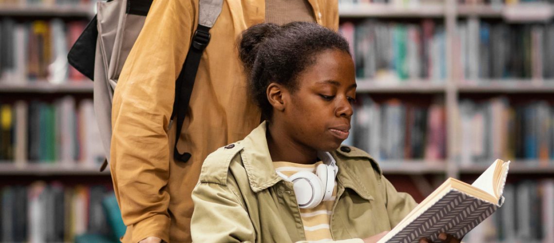 girl-helping-her-colleague-wheelchair-choose-book-project